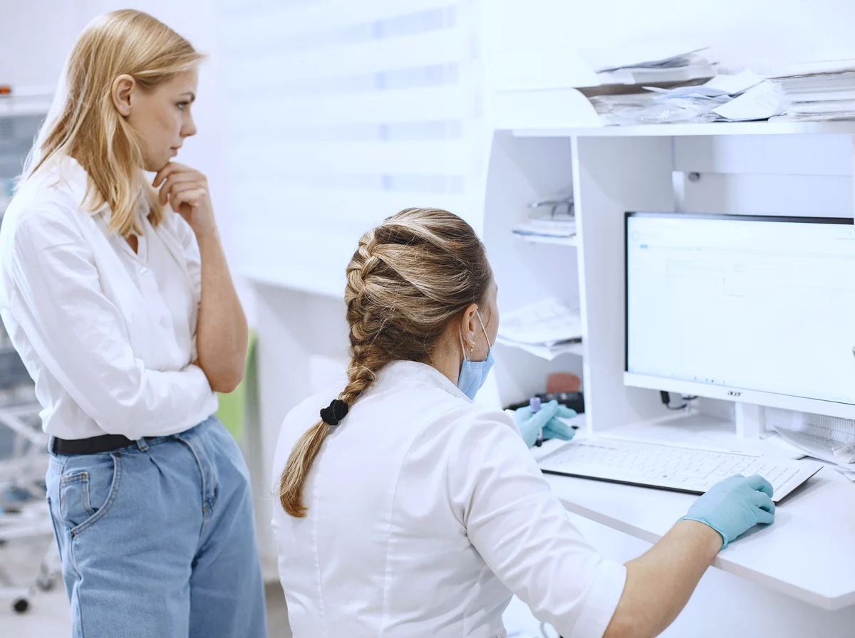 Coordenadora de escalas gerenciando plantões em um monitor com grade de horários
